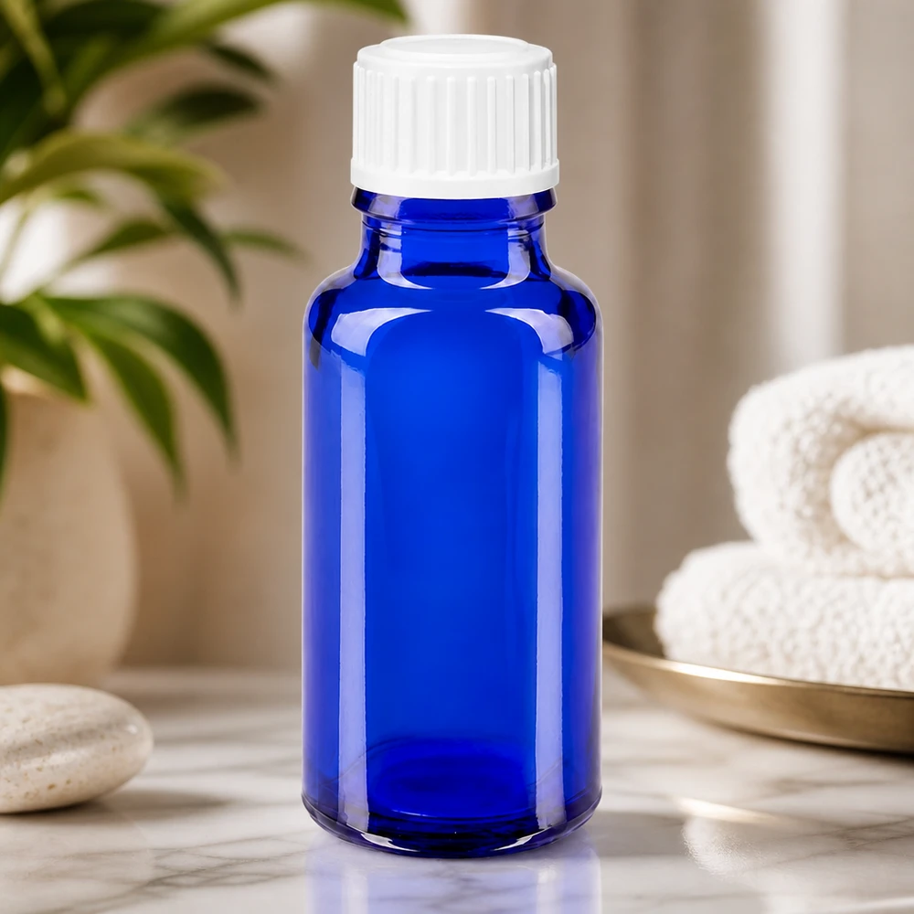 Flacone da farmacia in vetro blu da 20 ml con tappo contagocce bianco su fondo marmorizzato
