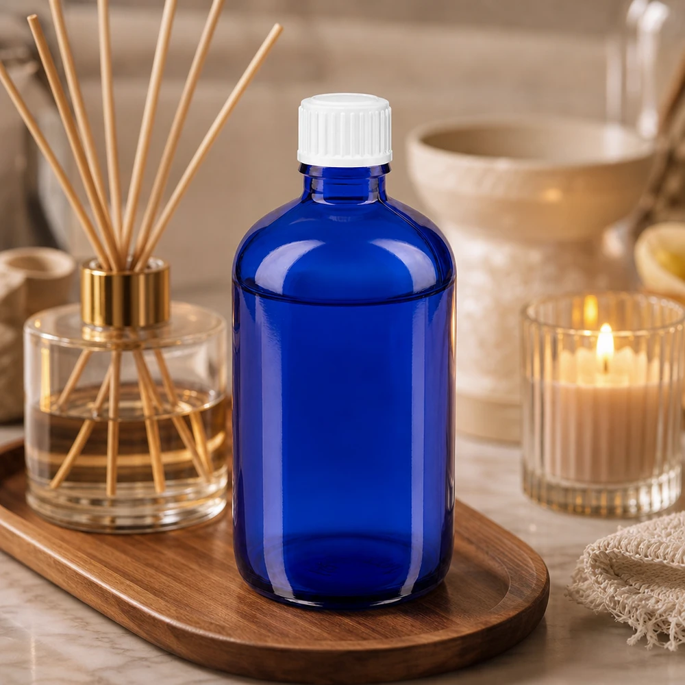 Fiaschetta rotonda da 100 ml in vetro blu cobalto con tappo a vite bianco, su vassoio di legno