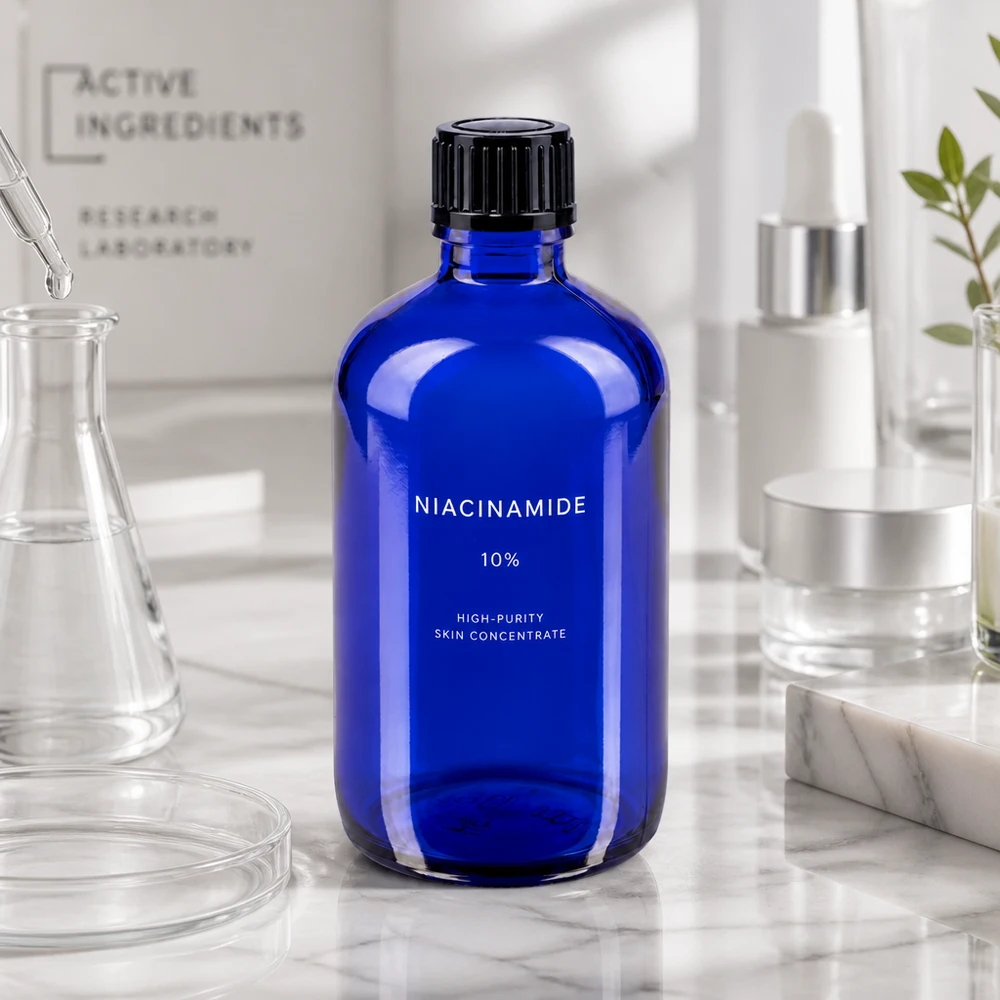 Flacone da farmacia da 100 ml blu cobalto con etichetta alla niacinamide su fondo marmorizzato in un ambiente da laboratorio