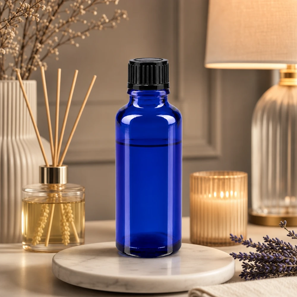 Flacone in vetro da farmacia blu da 30 ml con tappo contagocce nero, accanto a lavanda e diffusore di profumo per ambienti