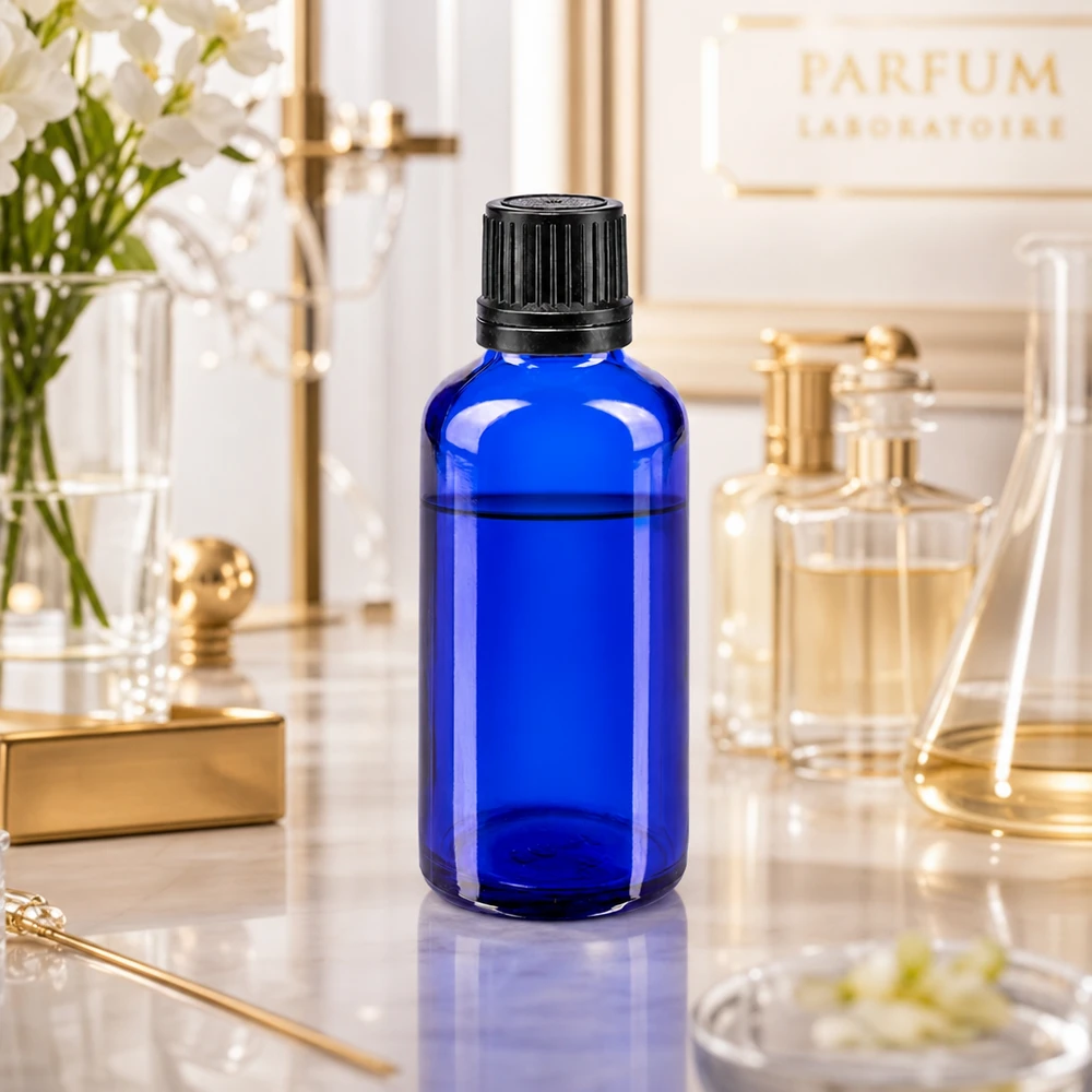 Flacone contagocce blu da 50 ml con inserto di precisione da 1 mm, in un’elegante ambientazione da laboratorio di profumi