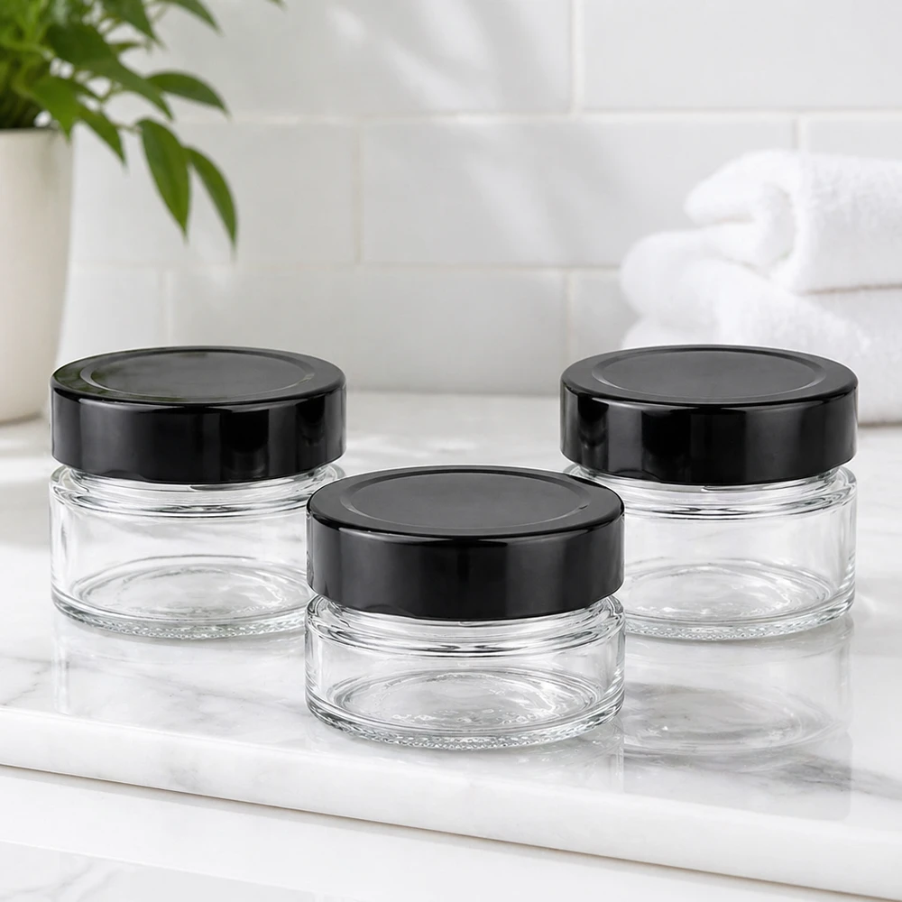 Barattolo rotondo da 80 ml + coperchio BasicSeal nero profondo UNiTWIST Tre barattoli rotondi da 80 ml con coperchi neri BasicSeal UNiTWIST su piano in marmo bianco Ambiente bagno vuoto