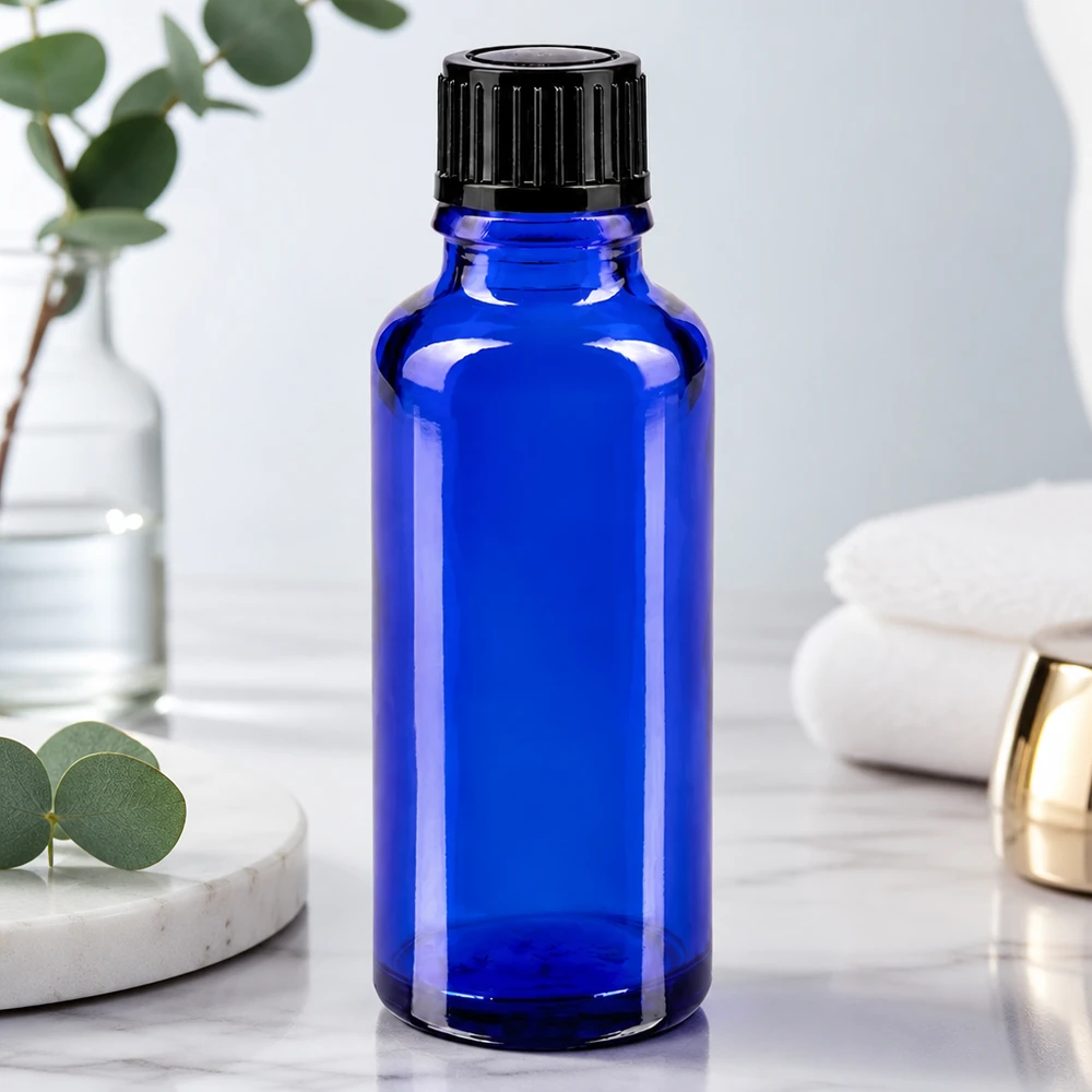 Flacone di vetro da 30 ml blu cobalto con tappo a vite nero su una superficie in marmo bianco