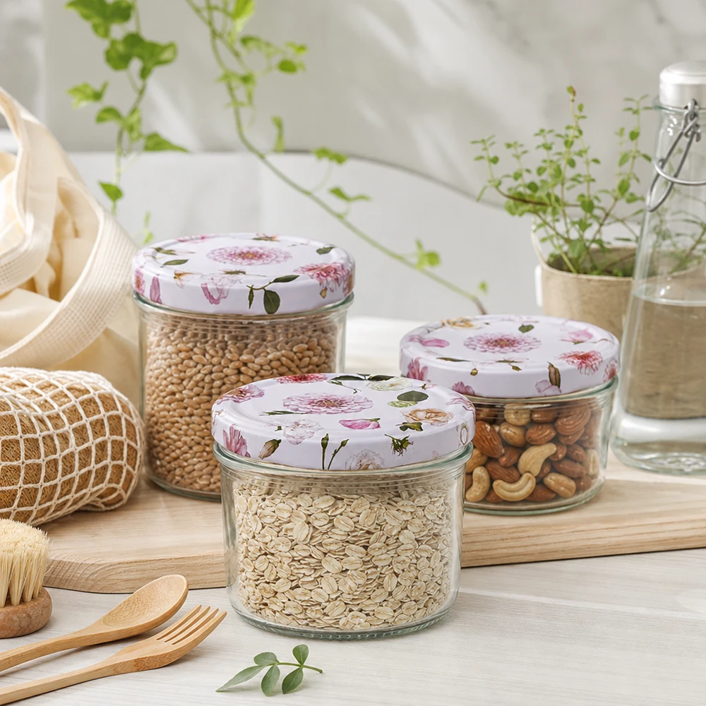 Barattolo cilindrico da 230 ml + coperchio BasicSeal rosa fiore Tre barattoli cilindrici da 230 ml con coperchi a fiore rosa riempiti di cereali e frutta secca in un ambiente di cucina sostenibile