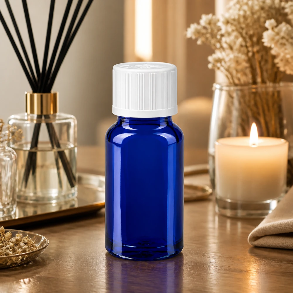 Bottiglia da farmacia blu da 10 ml. SV STD KiSi bianco/11mm ApoGlas Piccola boccetta di vetro blu da 10 ml con tappo a vite bianco su un tavolino di legno accanto a un diffusore di profumo per ambienti e a una candela