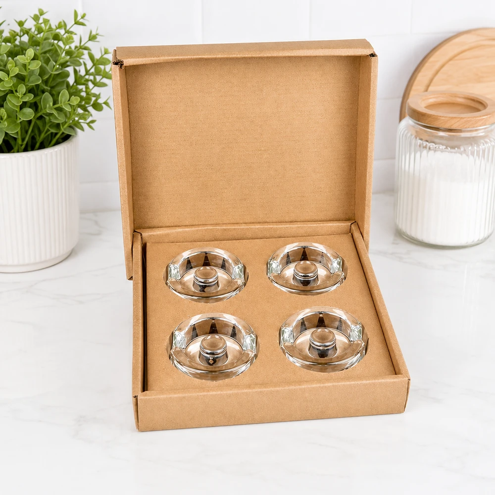 Pesi in vetro per fermentazione con manico set di 4 UNiTWIST Set di 4 pesi per vasi di fermentazione UNiTWIST aperti in una scatola marrone accanto a un vaso per piante e a un vaso per la conservazione.