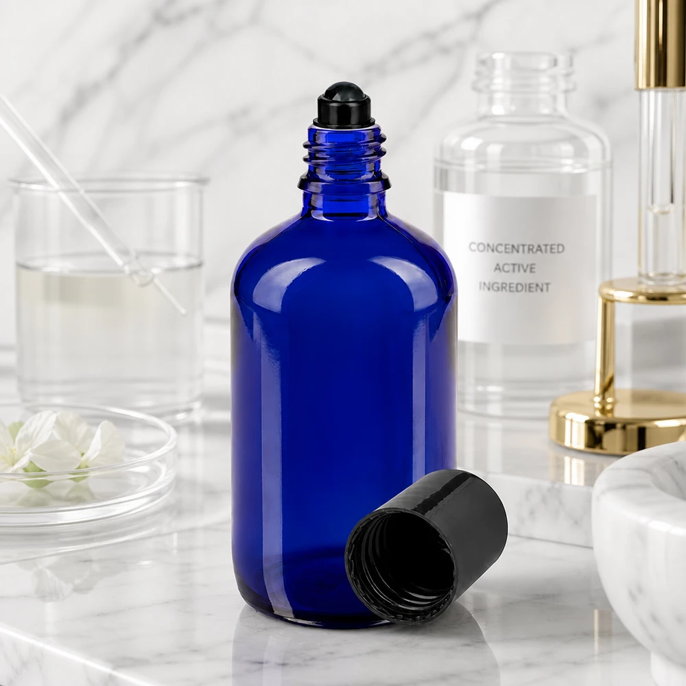 Flacone roll-on 100ml blu STD nero ApoGlas Flacone roll-on da 100 ml aperto, di colore blu cobalto con applicatore a sfera nero, in un ambiente di laboratorio