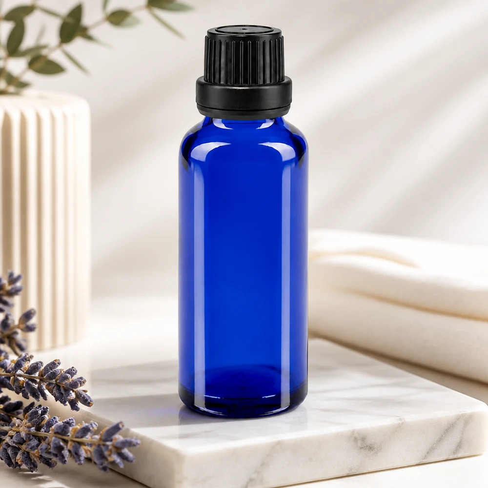 Flacone contagocce ApoGlas blu da 30 ml con inserto da 2 mm e tappo nero accanto a un mazzetto di lavanda su marmo