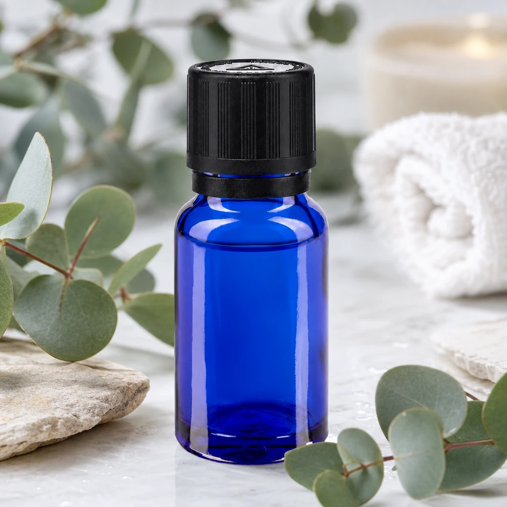 Flacone da farmacia da 10 ml blu cobalto con tappo OV nero su fondo marmorizzato, tra rami di eucalipto