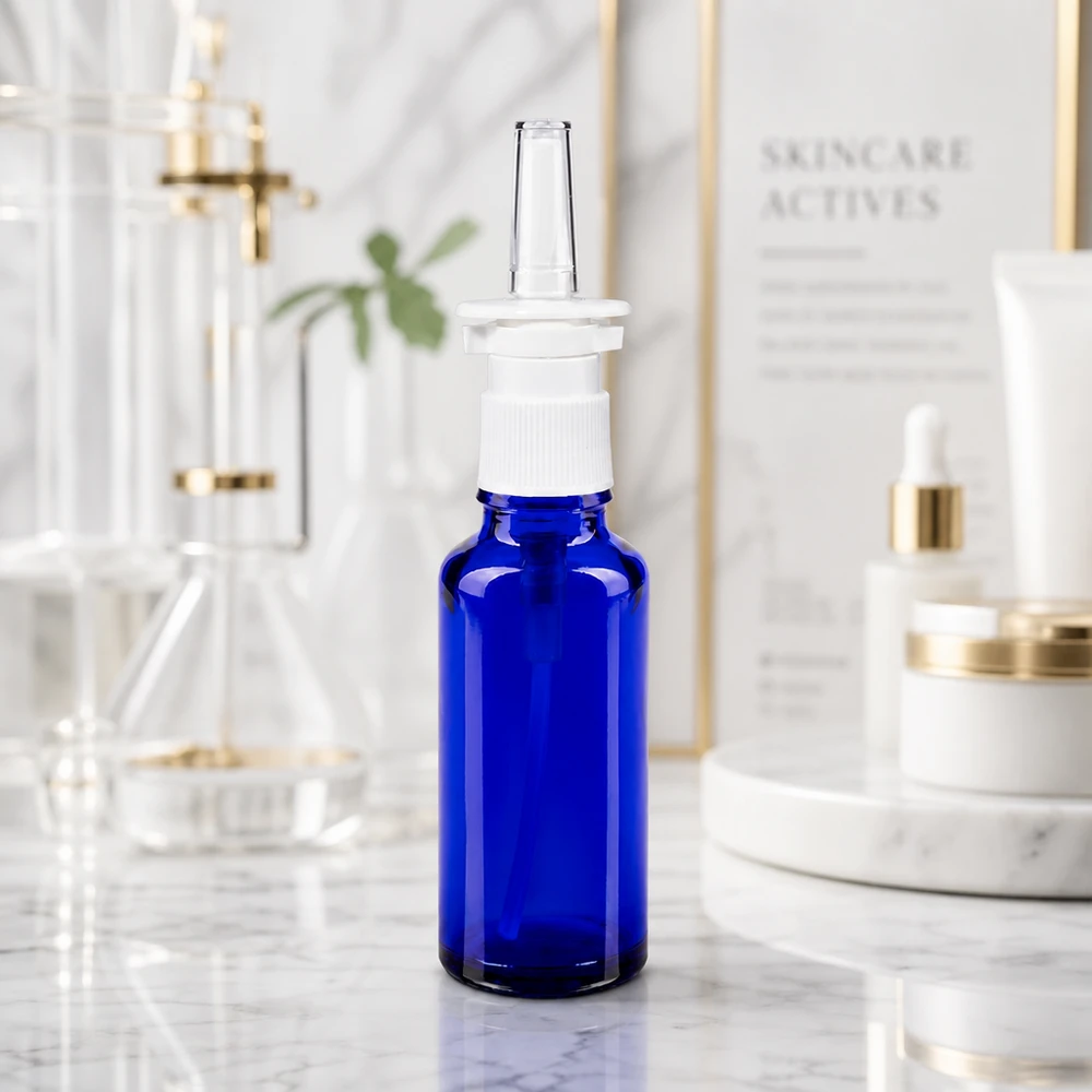 Flacone in vetro blu cobalto da 30 ml con erogatore a pompa bianco su sfondo marmorizzato