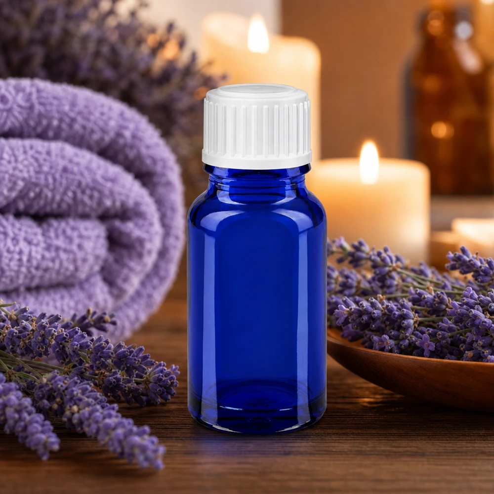 Flacone 10ml blu (Glo.) GR STD bianco/3mm ApoGlas Flacone di vetro blu da 10 ml con tappo bianco, circondato da fiori di lavanda e candele