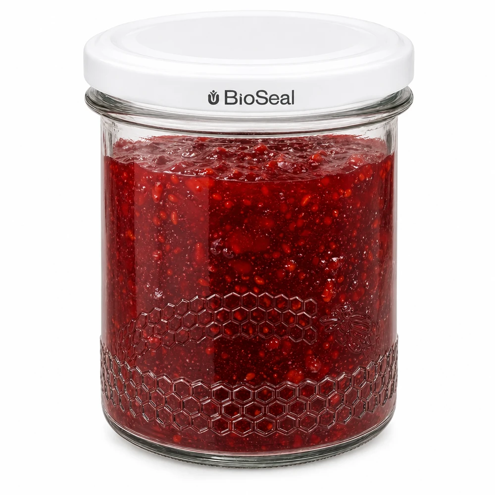 Vasetto per miele da 560 g con capsula bianca BioSeal UNiTWIST Il barattolo BioSeal da 400 ml riempito di marmellata rossa mostra la chiusura ermetica e la goffratura a nido d'ape sul bordo del barattolo.