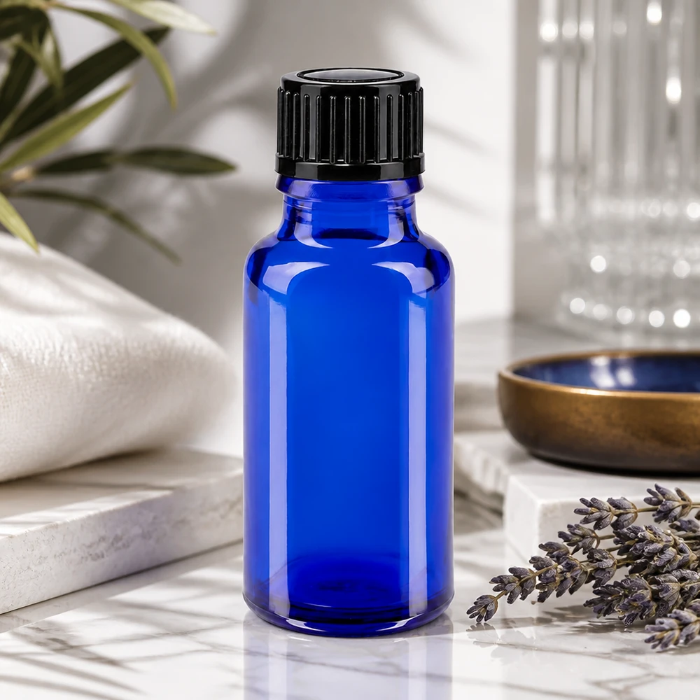 Flacone da farmacia blu da 20 ml con tappo a vite nero accanto a rametti di lavanda su marmo