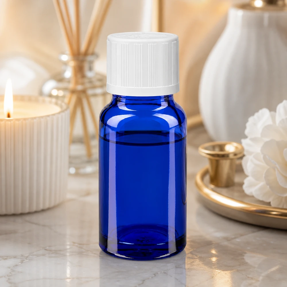 Contagocce blu da 10ml. STD KiSi bianco/1,2mm ApoGlas Piccola bottiglia di vetro blu con tappo a vite bianco su una superficie di marmo, accanto a una candela e a un diffusore