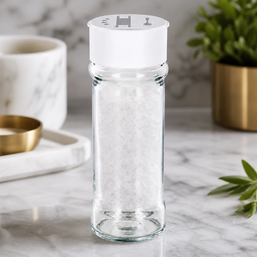 Barattolo per sale/spezie da 100 ml con doppio dosatore, bianco Barattolo trasparente per spezie da 100 ml con doppio spargitore bianco su base in marmo, riempito con sale marino grosso