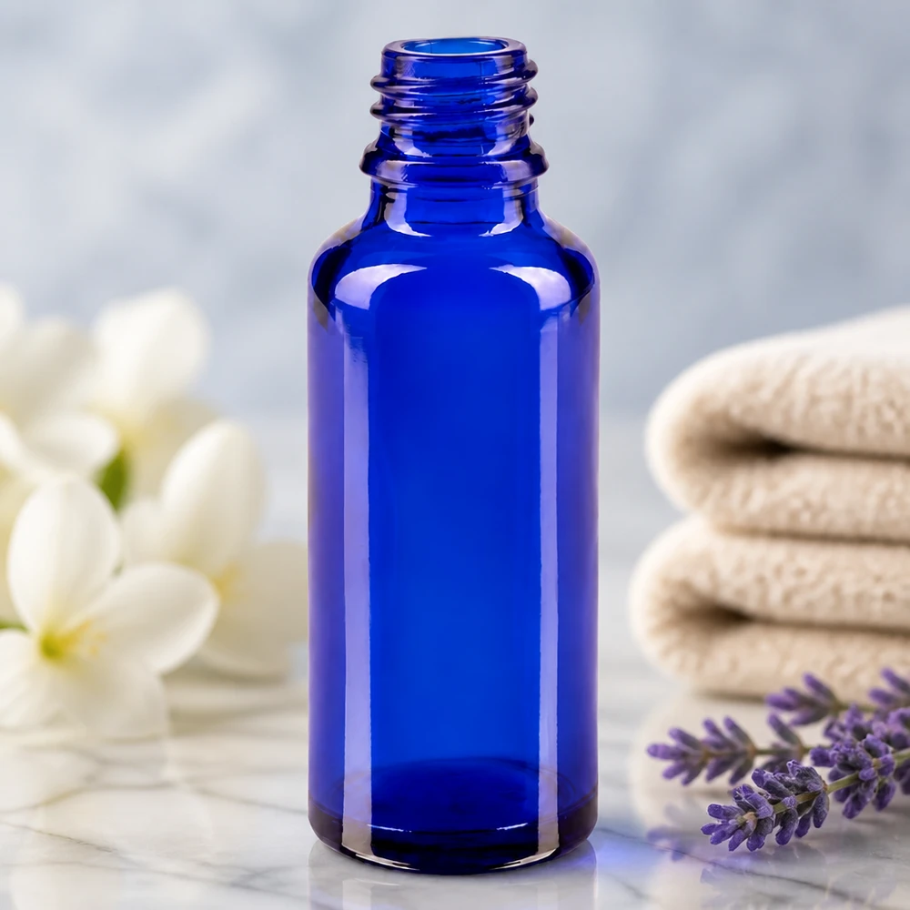 Flacone da farmacia ApoGlas vuoto da 30 ml, di colore blu reale, accanto a un rametto di lavanda e a fiori bianchi