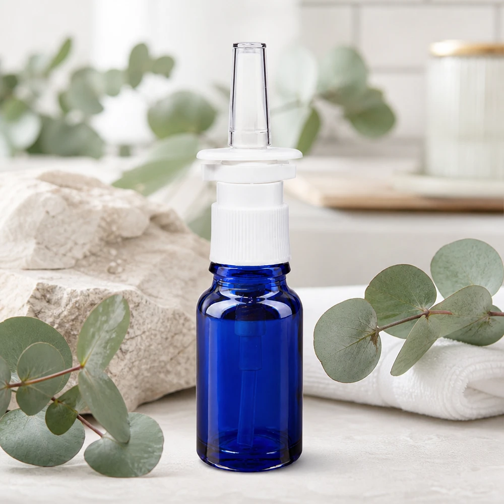 Flacone di vetro blu da 10 ml con beccuccio trasparente per spray nasale su sfondo naturale di eucalipto