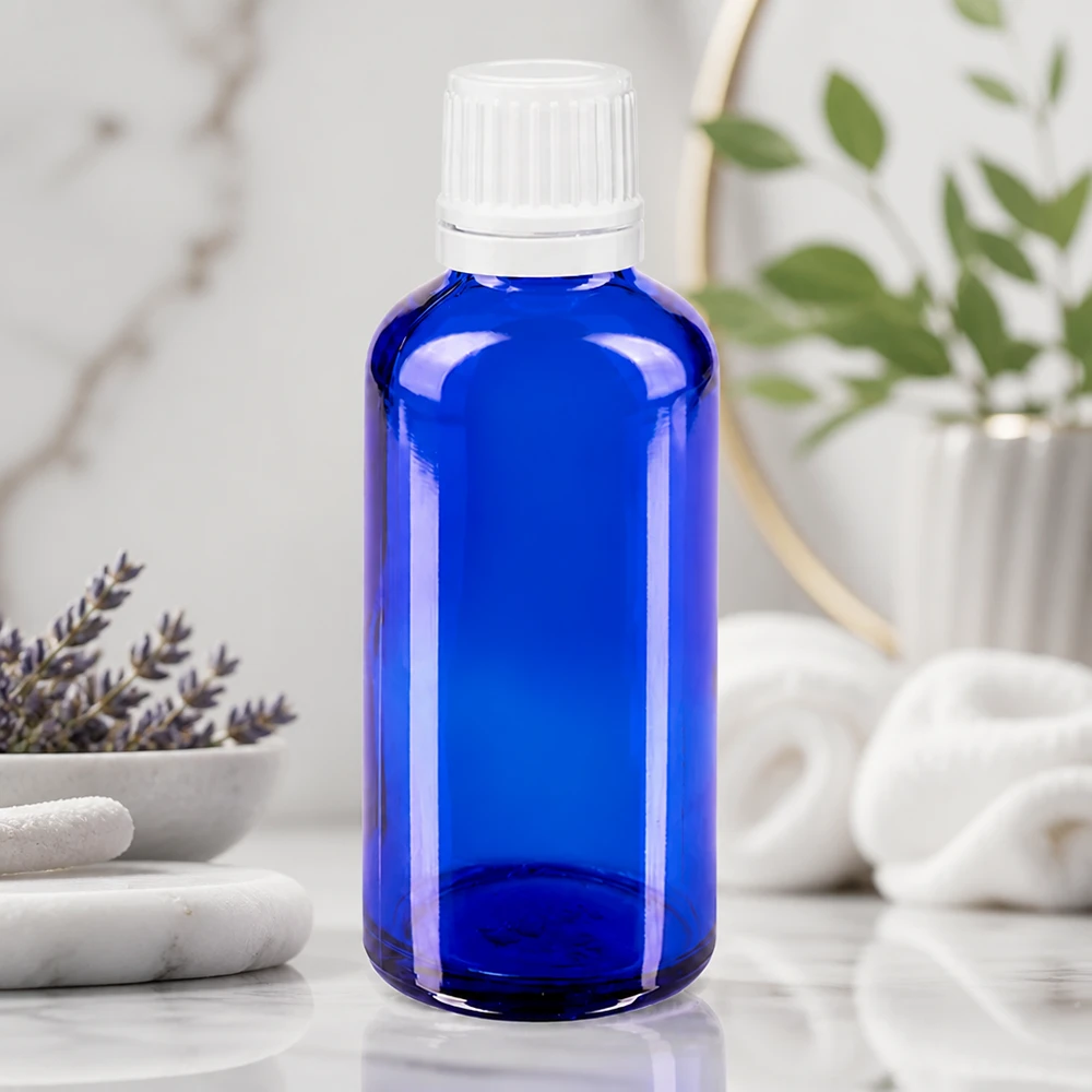 Bottiglia di vetro blu da 50 ml con tappo a vite bianco su una superficie di marmo accanto alla lavanda