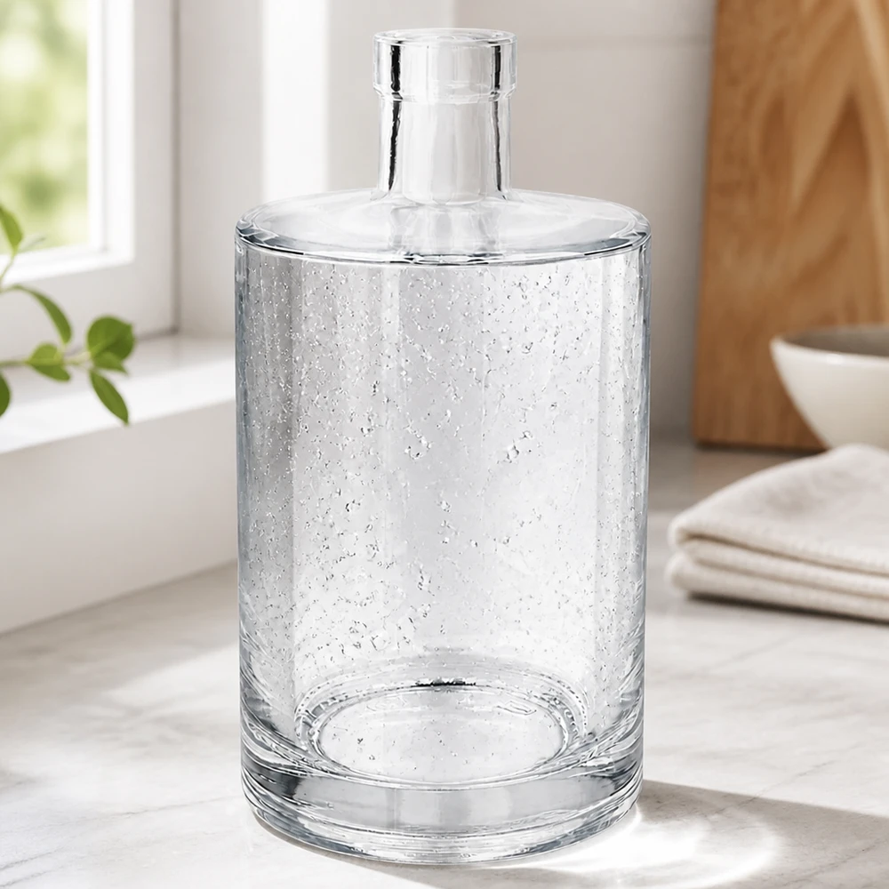 Bottiglia in vetro da 700 ml Marie senza tappo UNiTWIST® Elegante 700ml Glasflasche Marie mit Luftbläschen-Optik in modernem Wohnambiente neben Handtüchern und Holzschale
