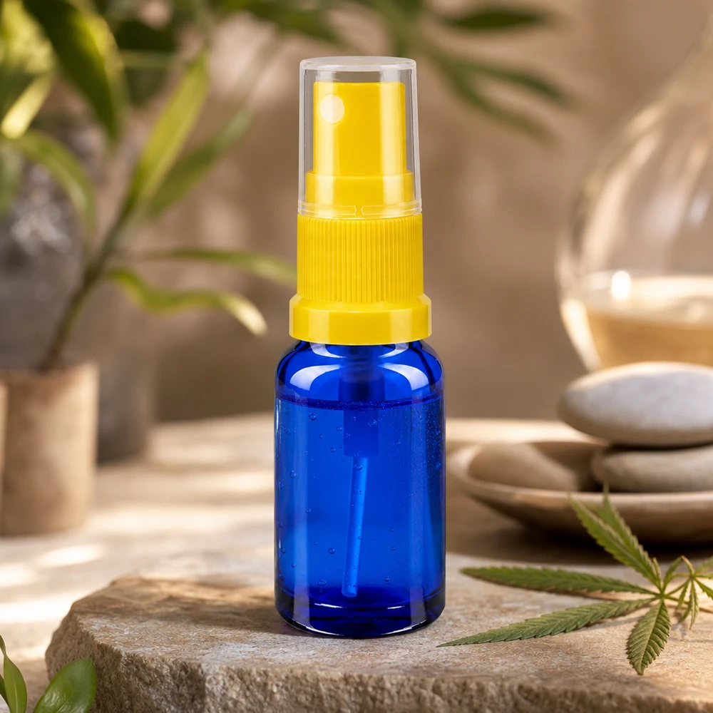 Mini flacone contagocce blu da 10 ml con erogatore a spruzzo giallo trasparente su pietra naturale con foglia di cannabis