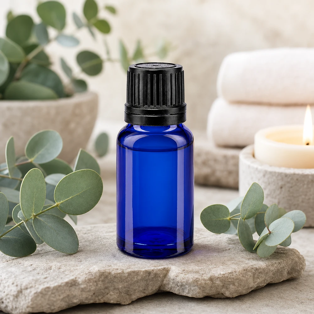Flacone contagocce blu da 10 ml con tappo a vite nero, appoggiato su una pietra naturale con ramoscelli di eucalipto