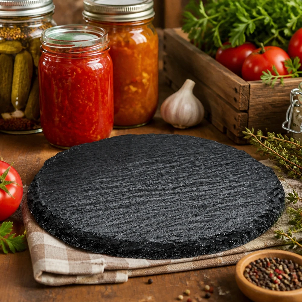 Lastra di ardesia rotonda da 150 mm in cucina rustica, decorata con barattoli di conserva, pomodori ed erbe aromatiche come piano di servizio