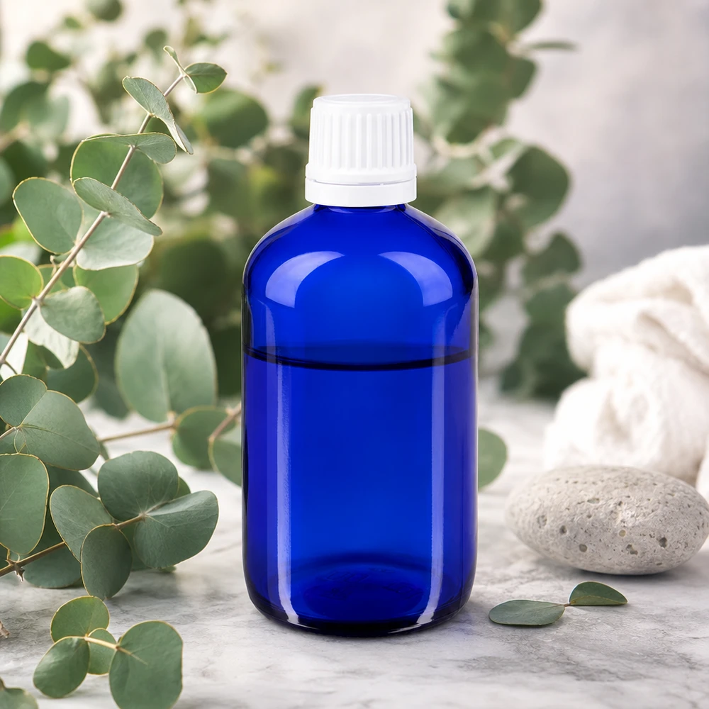 Flacone contagocce blu da 20 ml in vetro da farmacia con tappo bianco KiSi su base in marmo con eucalipto