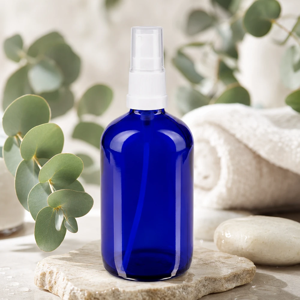 Flacone spray blu 100ml STD bianco/trasp. apoGlas Flacone spray rotondo da 100 ml in vetro blu con protezione UV, con erogatore a pompa bianco su base in pietra naturale