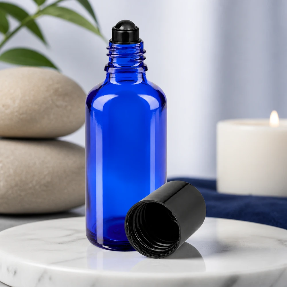 Flacone roll-on 50ml blu STD nero ApoGlas Flacone di vetro blu da 50 ml con applicatore roll-on nero e tappo rimosso su fondo di marmo