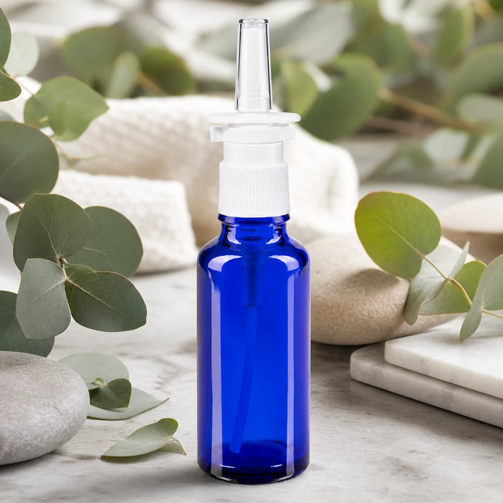 Flacone spray nasale da 30 ml, blu cobalto, con erogatore bianco e rametti di eucalipto come decorazione naturale