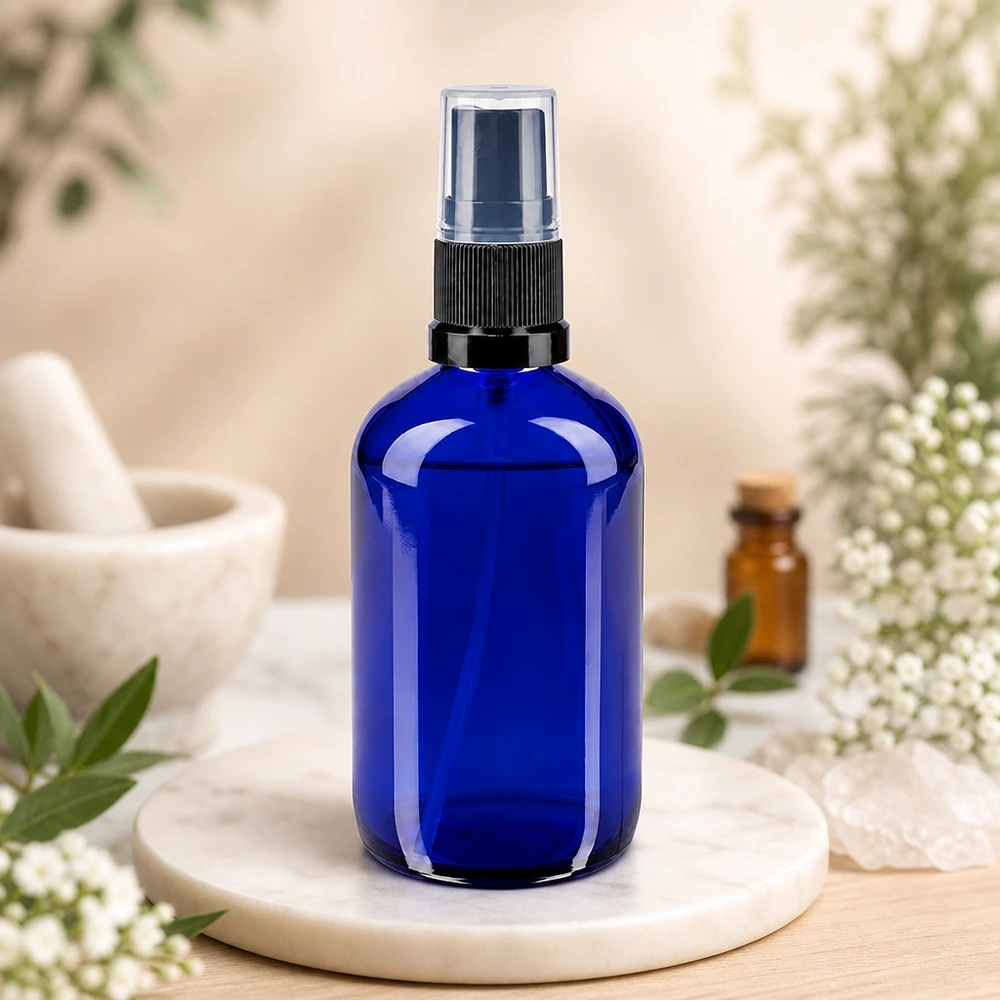 Flacone spray blu da 100 ml. STD nero/trasp. ApoGlas Flacone spray blu da 100 ml in vetro da farmacia con nebulizzatore nero su vassoio in marmo