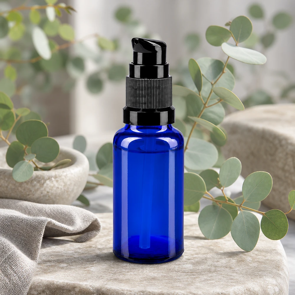 Fiaschetta da farmacia blu da 20 ml con pompa dosatrice nera, davanti a rami di eucalipto
