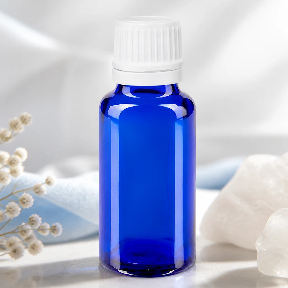 Bottiglia da farmacia blu da 20ml. SV OV bianco/11mm ApoGlas Flacone da farmacia da 20 ml blu cobalto con tappo di sicurezza bianco, accanto a cristallo di rocca e fiori secchi