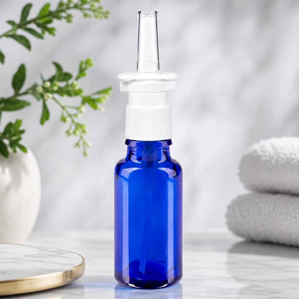 Flacone spray nasale 20ml blu bianco/tr. STD ApoGlas Flacone in vetro da farmacia blu da 20 ml con beccuccio trasparente per spray nasale e testina bianca su fondo marmorizzato