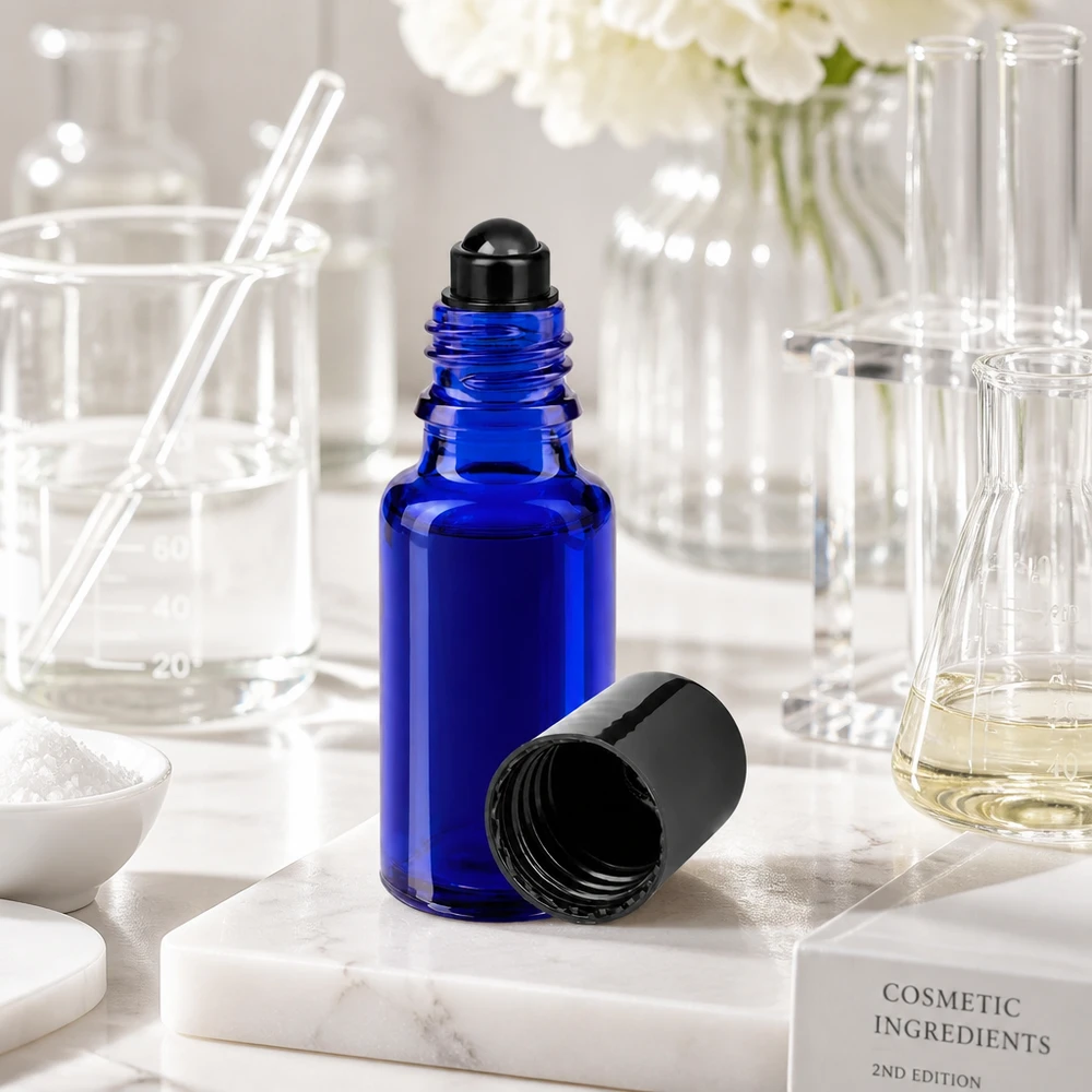 Flacone roll-on 20ml blu STD nero ApoGlas Flacone roll-on da 20 ml aperto, di colore blu con tappo nero, su una base in marmo