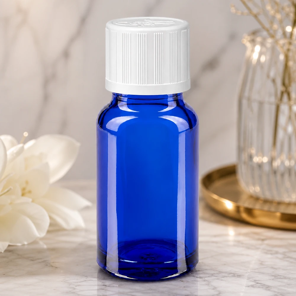 Flacone da farmacia da 10 ml blu cobalto con tappo di sicurezza per bambini bianco su superficie marmorizzata