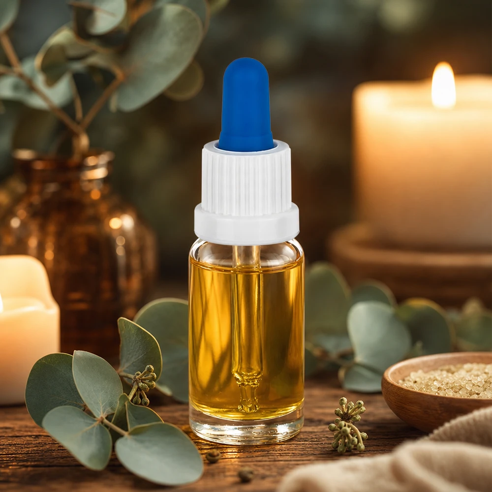 Flacone per pipette da 10 ml bianco/blu OV ClearL. UT18/10 Piccolo flacone con pipetta da 10 ml contenente olio dorato, con tappo bianco e pallina di gomma blu su un tavolino di legno