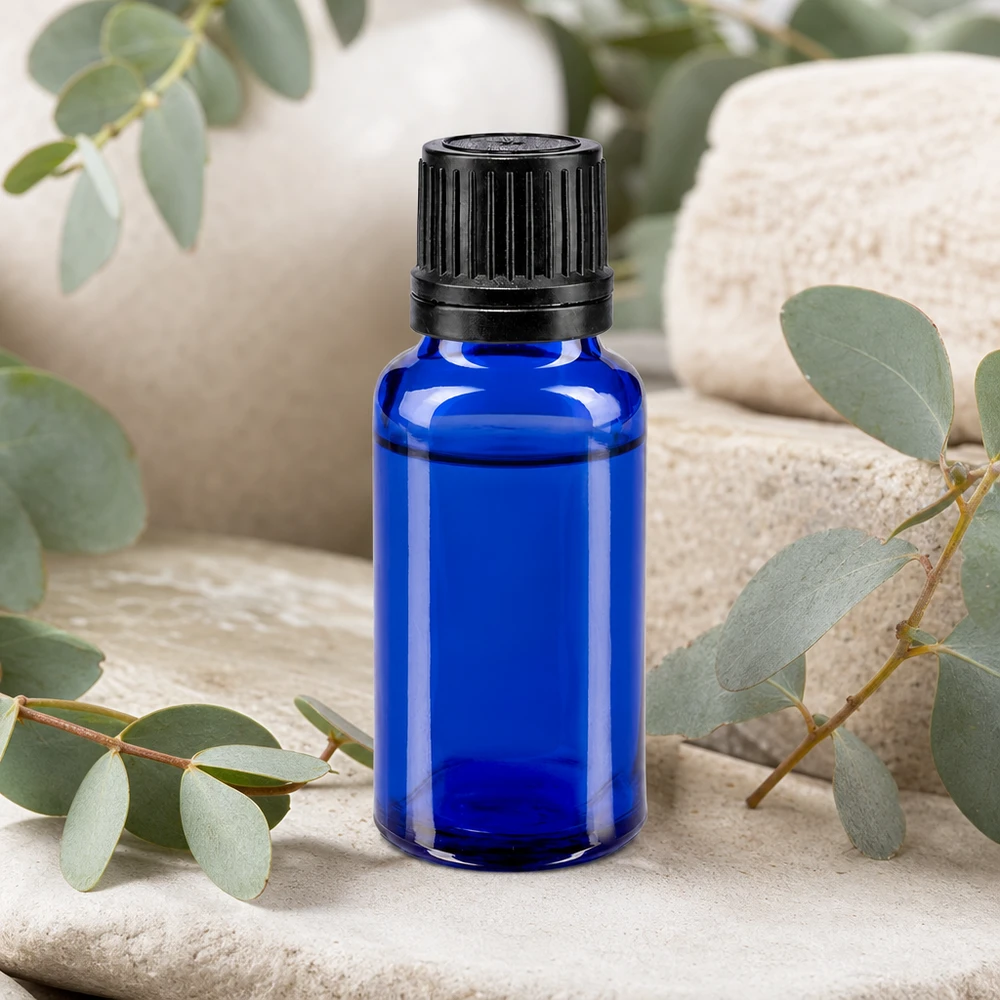 Fialetta in vetro da farmacia da 20 ml di colore blu cobalto con contagocce da 1 mm, disposta tra rami di eucalipto su una pietra naturale