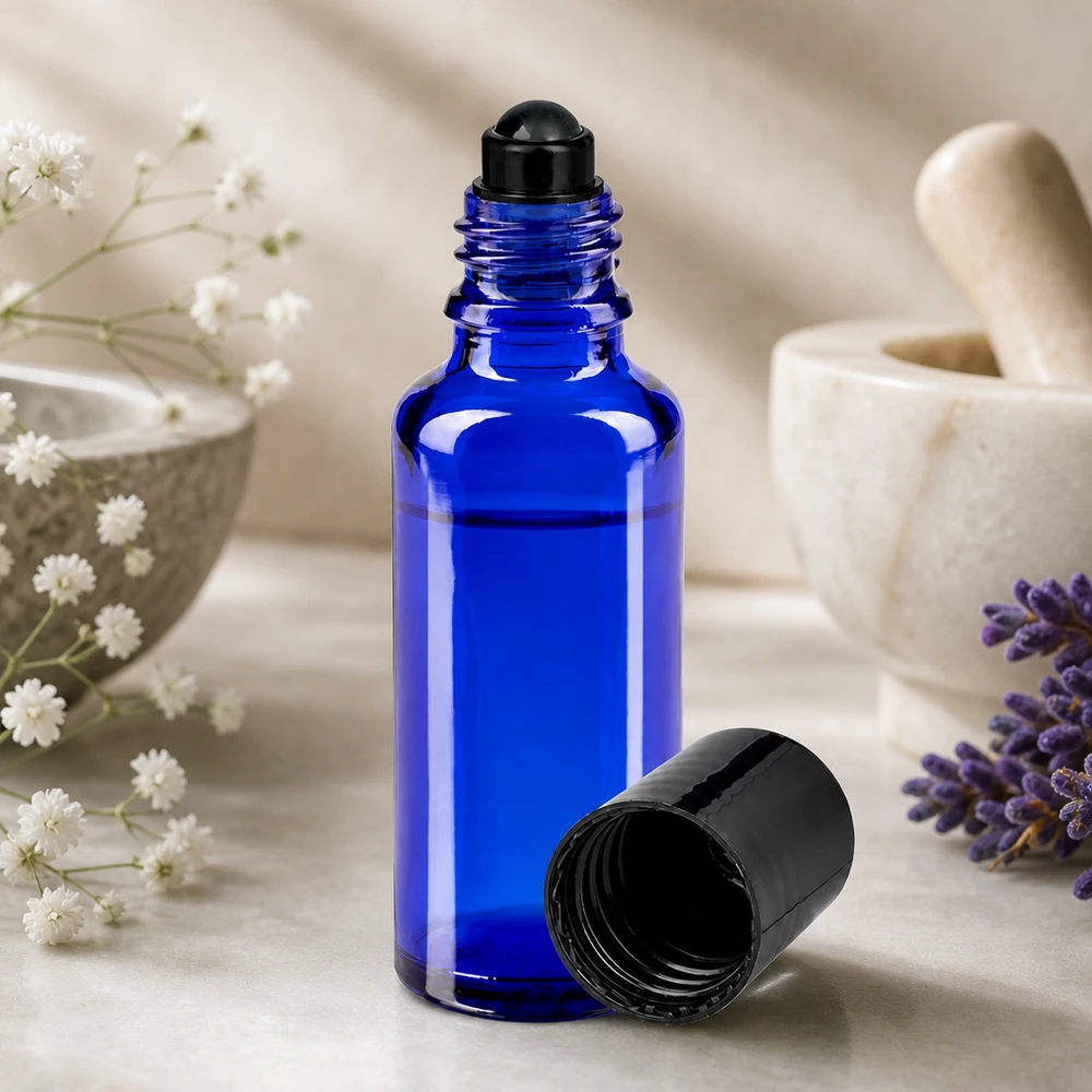 Flacone roll-on 30ml blu STD nero ApoGlas Flacone roll-on da 30 ml blu da farmacia con sferetta nera, accanto a una lavanda e a un mortaio