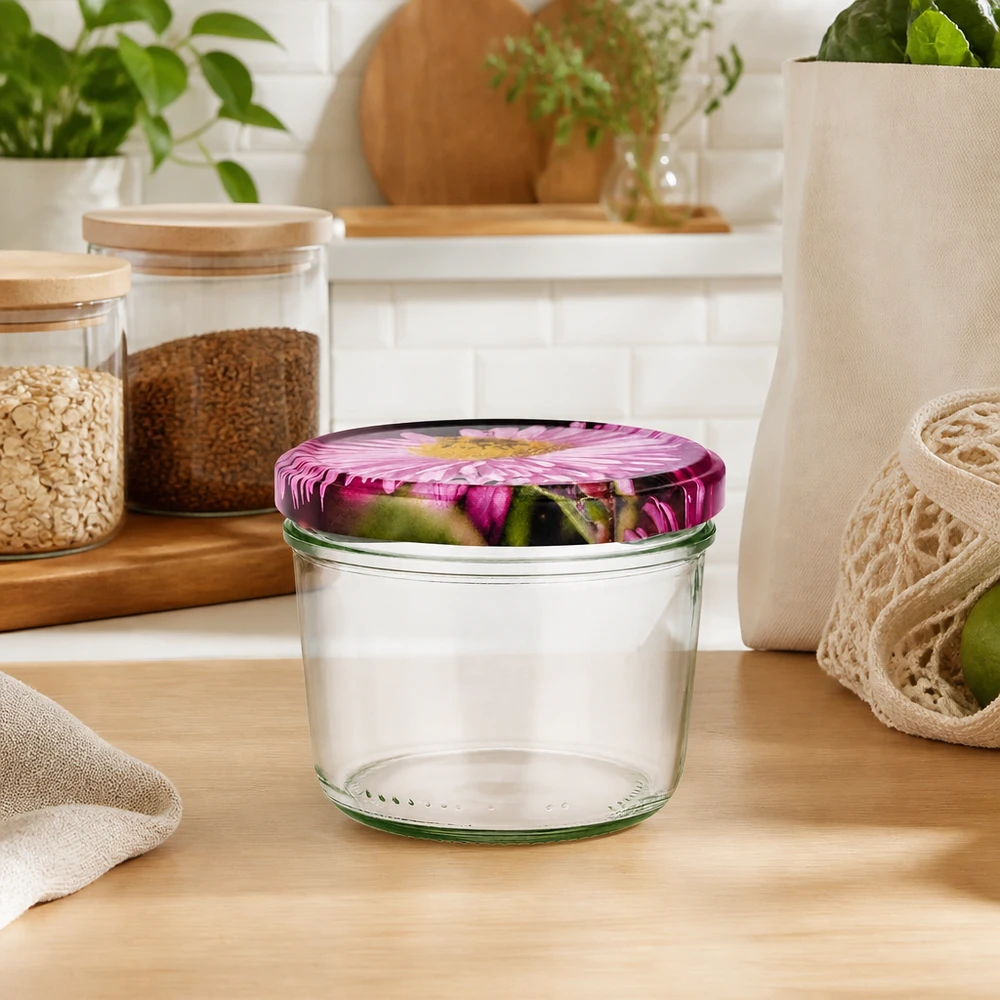 Bicchieri da 230 ml + coperchio BasicSeal design floreale UNiTWIST Sturzglas 230ml leer mit rosa Blütendeckel in natürlicher Küchenumgebung, umgeben von Vorratsgläsern und Pflanzen