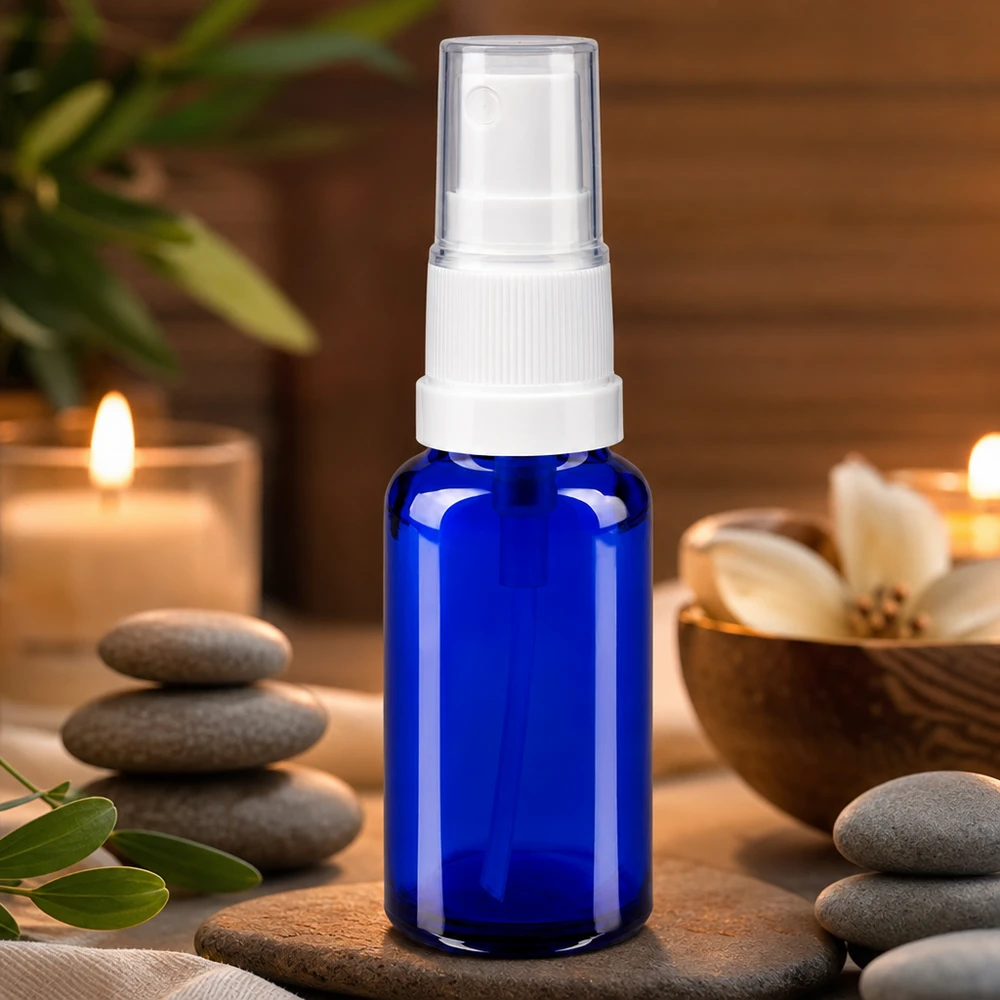 Flacone spray blu da 20ml STD bianco/trasp. apoGlas Flacone spray in vetro da farmacia blu da 20 ml con erogatore a pompa bianco, in un ambiente wellness-spa con candele