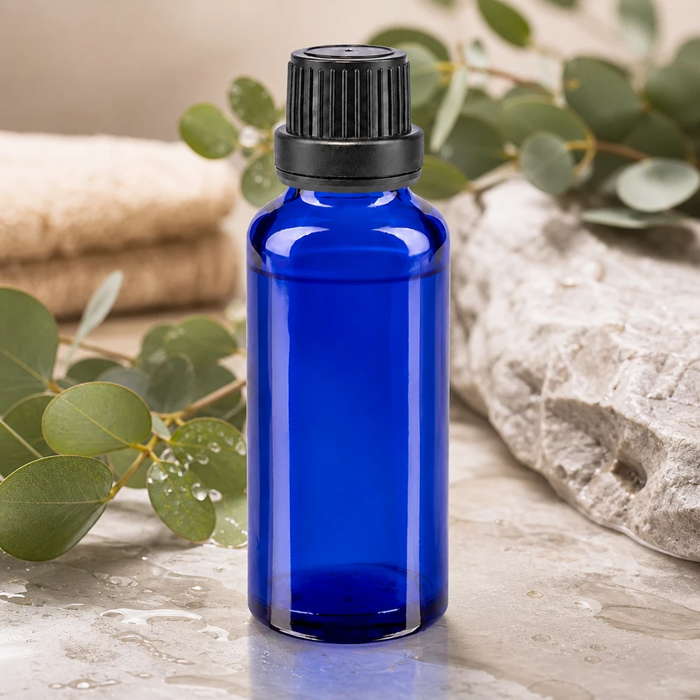 Flacone da farmacia da 30 ml blu cobalto con tappo OV nero su una base di pietra naturale con ramoscelli di eucalipto