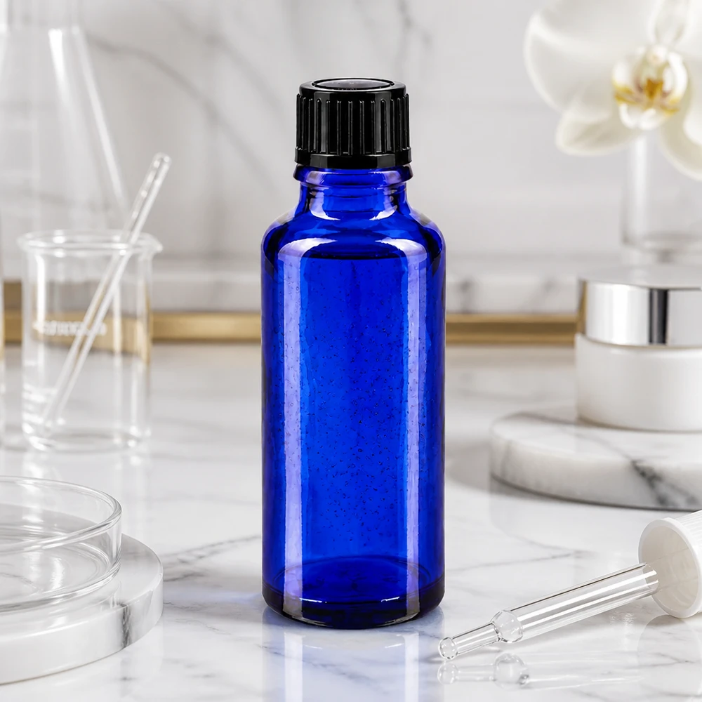 Flacone di vetro da 30 ml blu cobalto con tappo a vite nero su fondo di marmo bianco