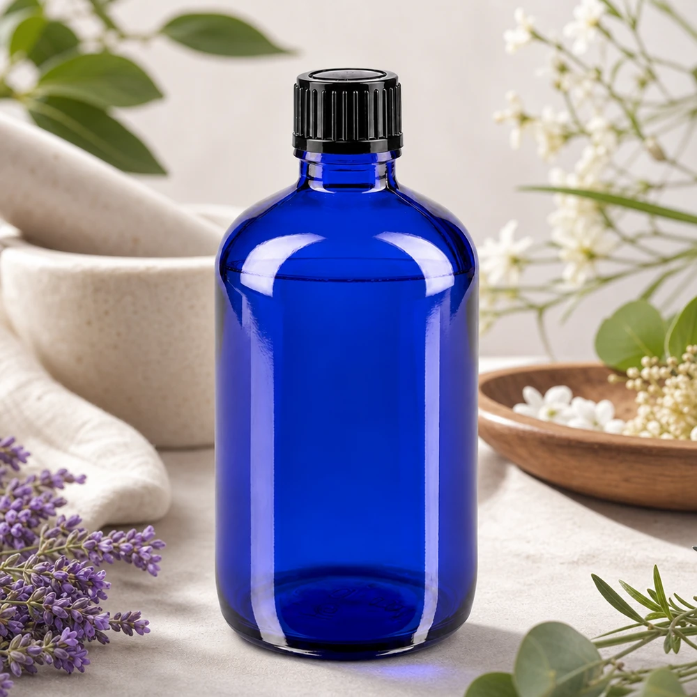 Bottiglia di vetro blu da 100 ml con tappo a vite, tra la lavanda e i fiori bianchi