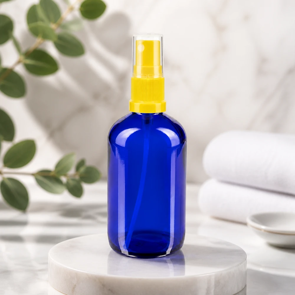 Flacone rotondo da 100 ml in vetro da farmacia blu con nebulizzatore a dito giallo su base in marmo