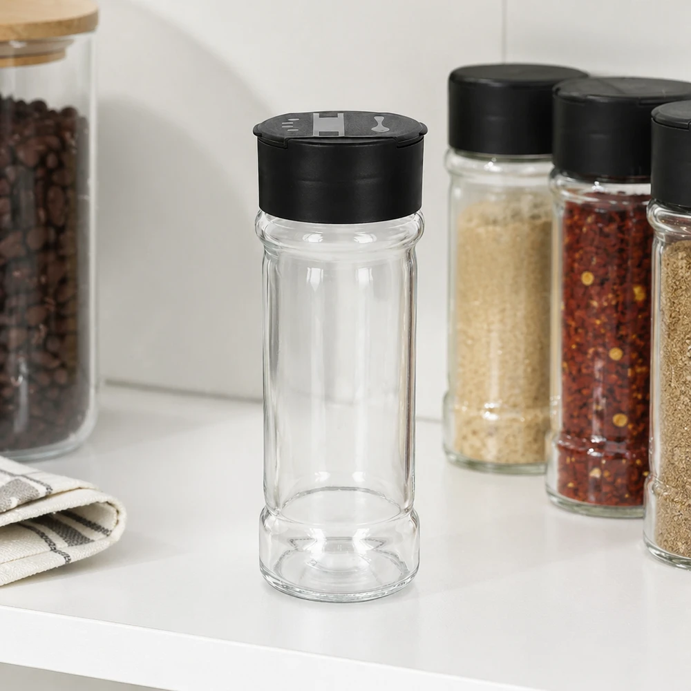 Barattolo per sale e spezie da 100 ml con doppio dosatore, nero Barattolo cilindrico per spezie da 100 ml con doppio dosatore nero, accanto a fiocchi di peperoncino e semi di sesamo