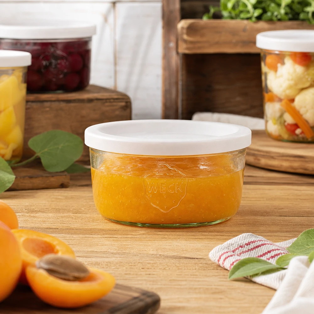 Vaso WECK da 165 ml riempito di marmellata di arance in un ambiente di cucina naturale con vasi da conserva sullo sfondo