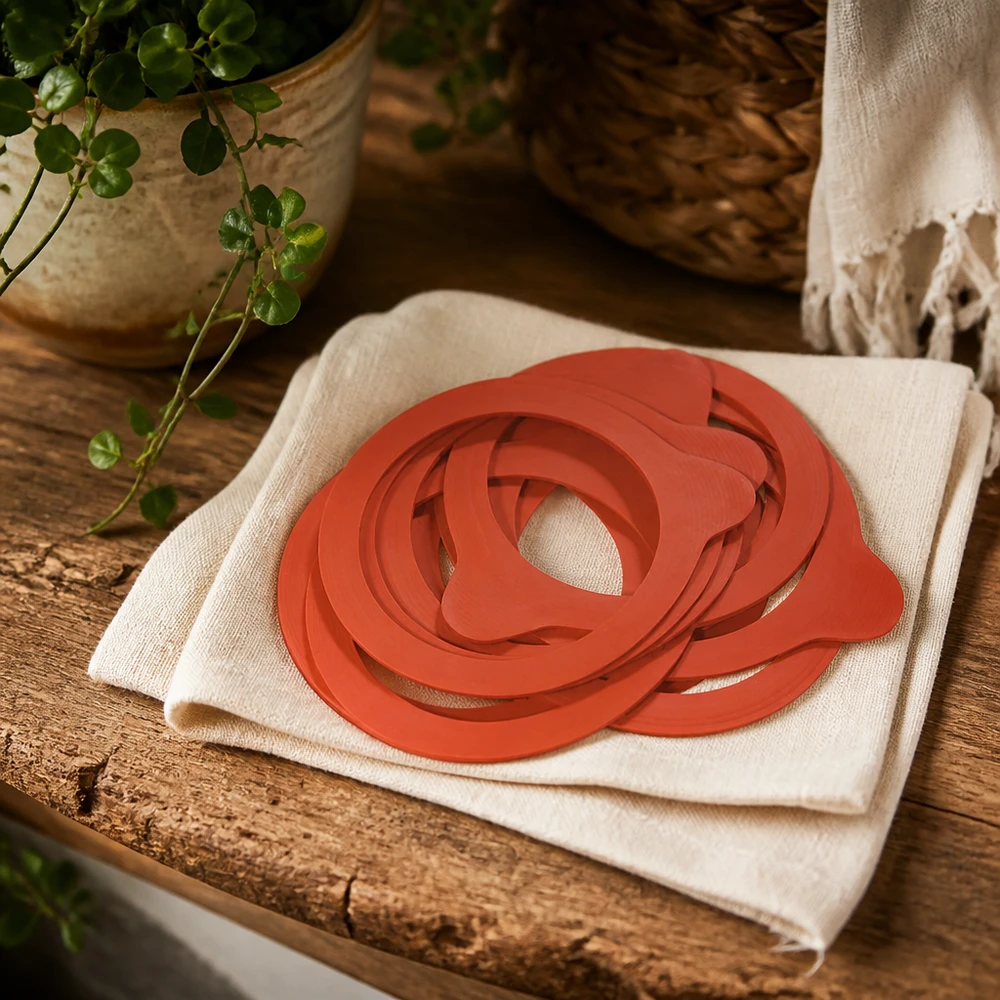 Anelli di conservazione RR60 gomma naturale arancione su panno di lino tavolo rustico in legno con pianta atmosfera naturale cucina