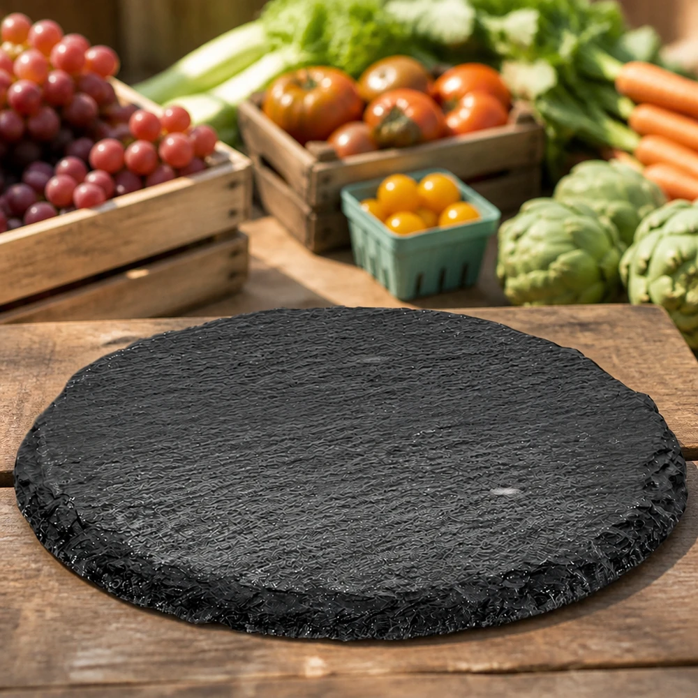 Piatto rotondo in ardesia da 15 cm tra verdure fresche e frutta come superficie di servizio naturale per formaggi e snack