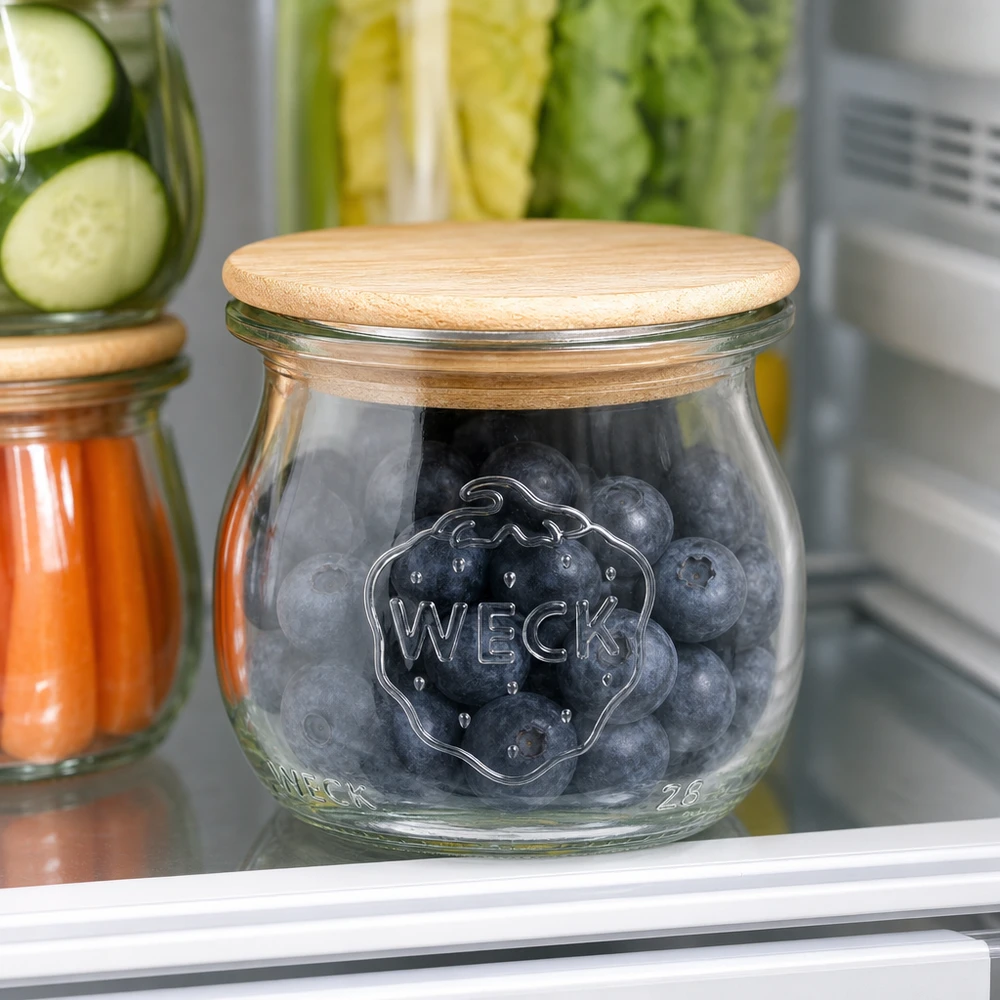 Barattolo WECK a tulipano RR40 75ml con coperchio in legno riempito di mirtilli in frigo accanto ad altri barattoli di conservazione